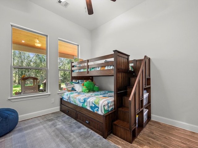 bedroom featuring a ceiling fan, visible vents, baseboards, and wood finished floors