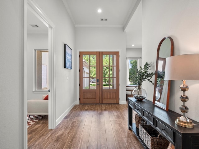 foyer featuring baseboards, visible vents, ornamental molding, and wood finished floors