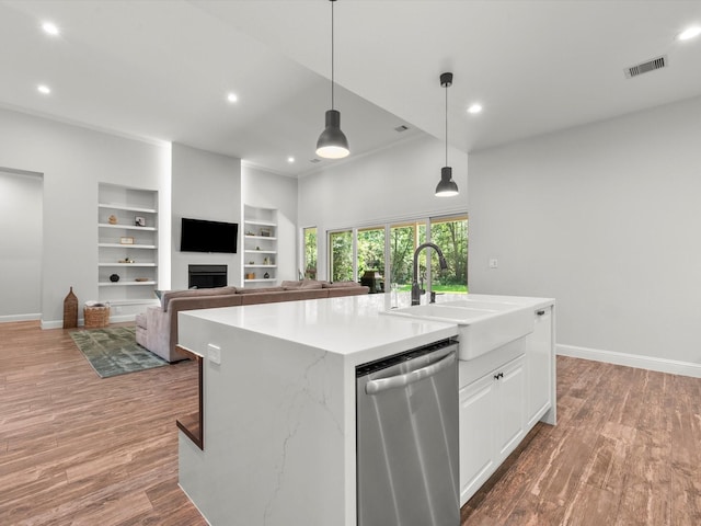 kitchen featuring a fireplace, stainless steel dishwasher, white cabinetry, a sink, and light wood-type flooring