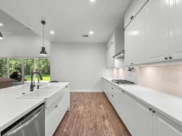 kitchen with stainless steel appliances, a sink, light countertops, backsplash, and dark wood-style floors