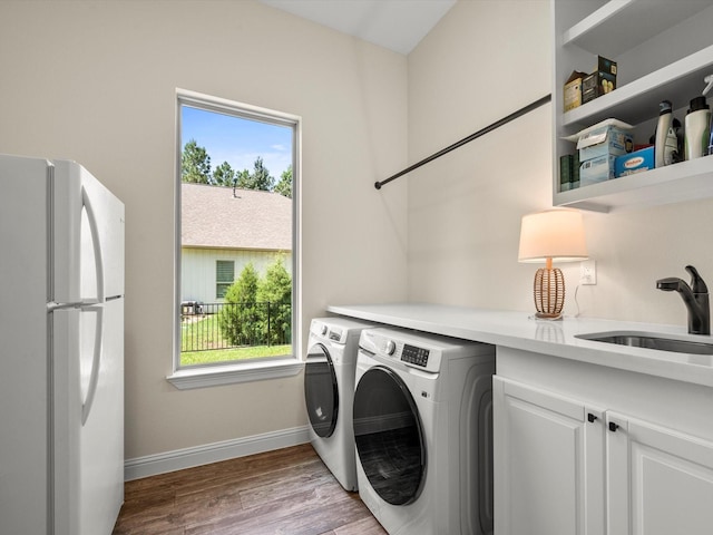 laundry room with a wealth of natural light, cabinet space, a sink, and wood finished floors