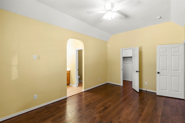 unfurnished bedroom featuring ceiling fan, connected bathroom, wood-type flooring, and a walk in closet