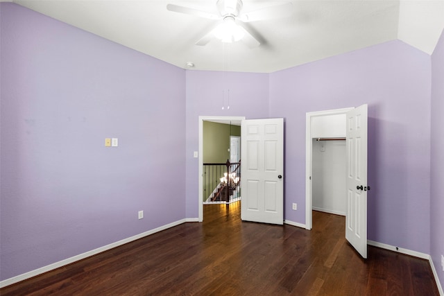 unfurnished bedroom with a walk in closet, a closet, ceiling fan, and dark hardwood / wood-style floors