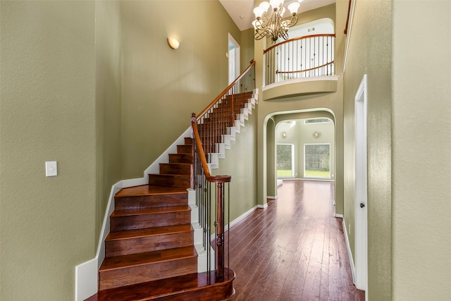 stairway featuring hardwood / wood-style floors, a high ceiling, and a chandelier