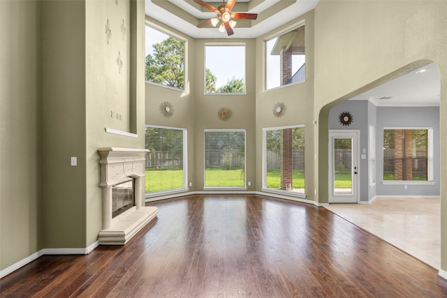 unfurnished living room featuring ceiling fan, a high ceiling, and wood-type flooring