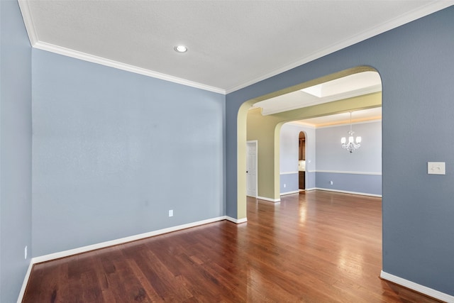 empty room featuring hardwood / wood-style flooring, crown molding, a textured ceiling, and an inviting chandelier