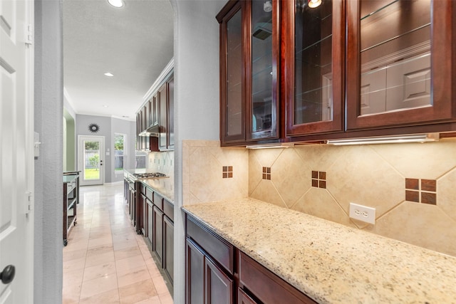 kitchen featuring stainless steel gas cooktop, tasteful backsplash, light stone counters, crown molding, and light tile patterned flooring