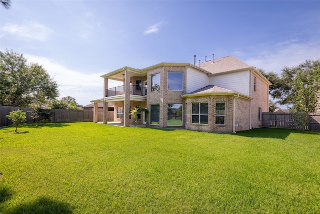 back of property with a yard and a balcony