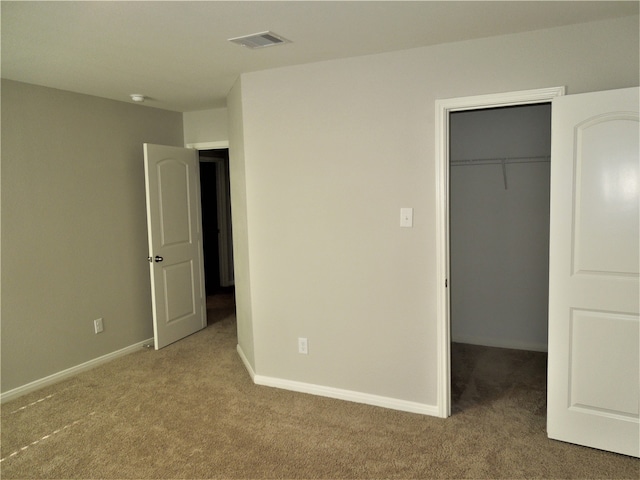 unfurnished bedroom featuring a walk in closet, carpet, and a closet