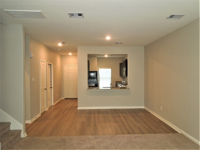 unfurnished living room featuring sink and wood-type flooring