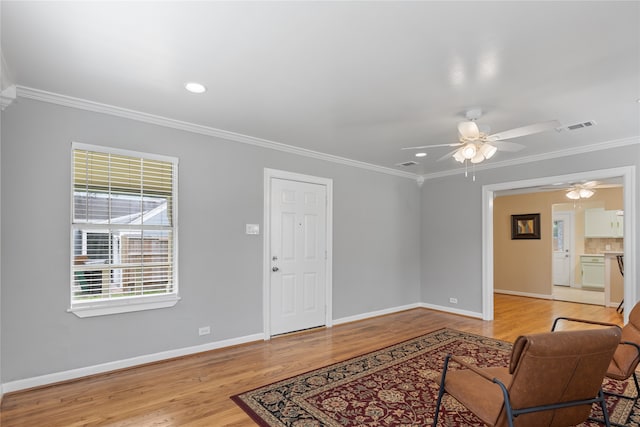 living room featuring ceiling fan, light hardwood / wood-style floors, and ornamental molding