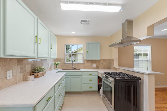 kitchen featuring backsplash, sink, light wood-type flooring, stainless steel gas range, and extractor fan