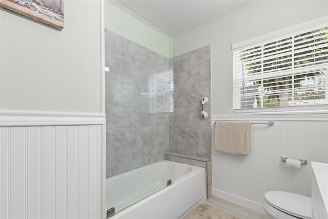 bathroom featuring tiled shower / bath combo and toilet