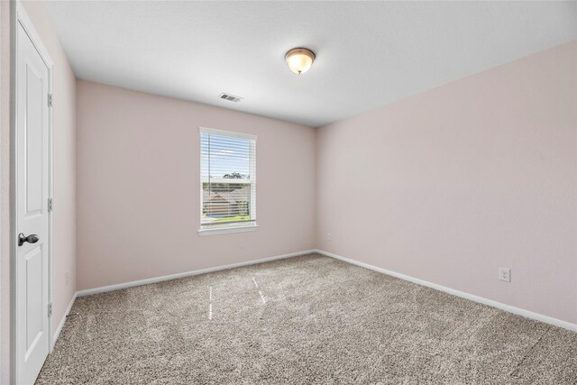 spare room featuring baseboards, visible vents, and carpet flooring