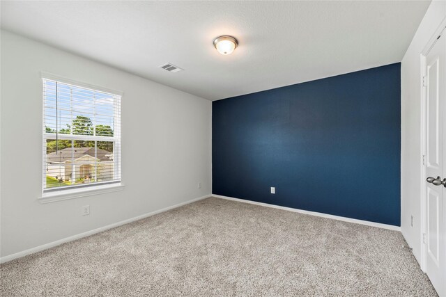 carpeted empty room featuring baseboards and visible vents