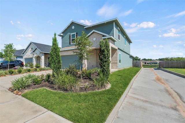 view of front of home featuring concrete driveway, brick siding, a front yard, and fence