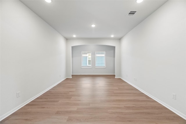 spare room featuring light wood-style floors, visible vents, arched walkways, and recessed lighting