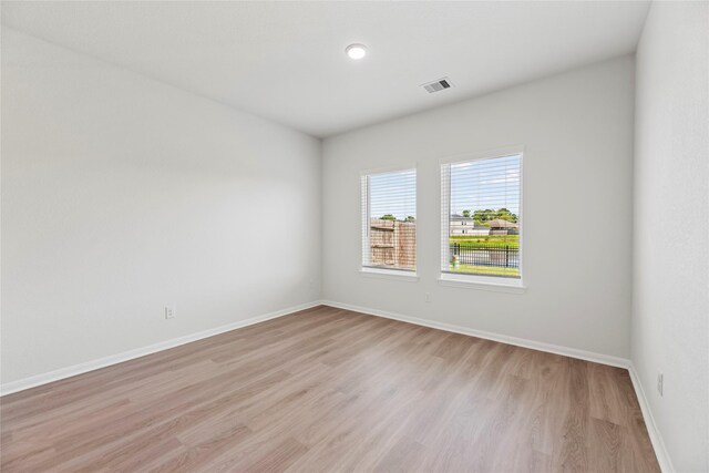 spare room featuring baseboards, visible vents, and light wood-style floors