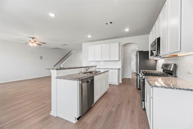 kitchen featuring arched walkways, a sink, visible vents, light wood-style floors, and appliances with stainless steel finishes