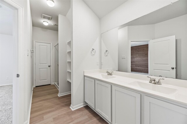 bathroom featuring double vanity, visible vents, a sink, and wood finished floors