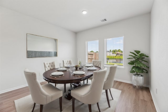 dining space with light wood-type flooring, visible vents, and baseboards