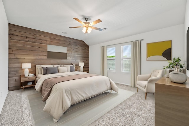 bedroom featuring lofted ceiling, wood walls, ceiling fan, and visible vents