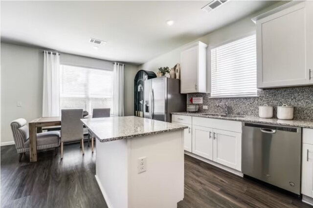 kitchen featuring stainless steel appliances, light stone counters, a kitchen island, dark wood-type flooring, and white cabinets