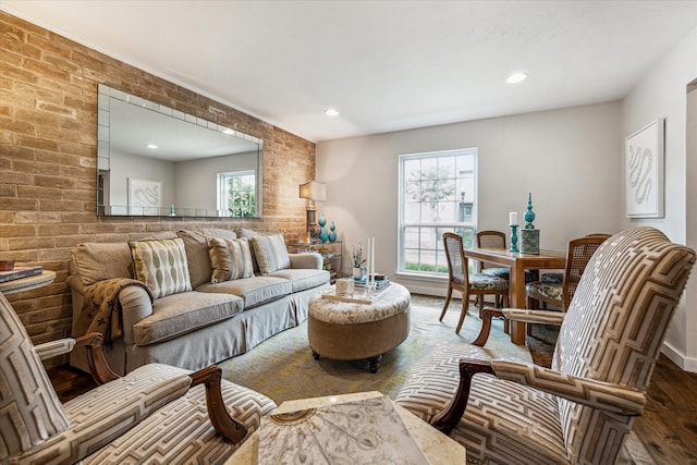 living room with a wealth of natural light, wood-type flooring, and brick wall