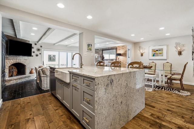 kitchen with dark hardwood / wood-style flooring, a fireplace, beam ceiling, light stone countertops, and gray cabinets