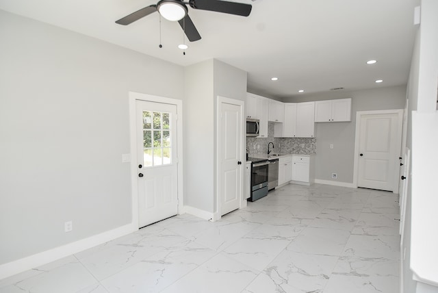 kitchen with appliances with stainless steel finishes, ceiling fan, white cabinetry, and light tile patterned floors