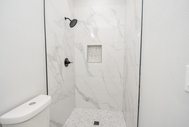 bathroom featuring toilet and a tile shower