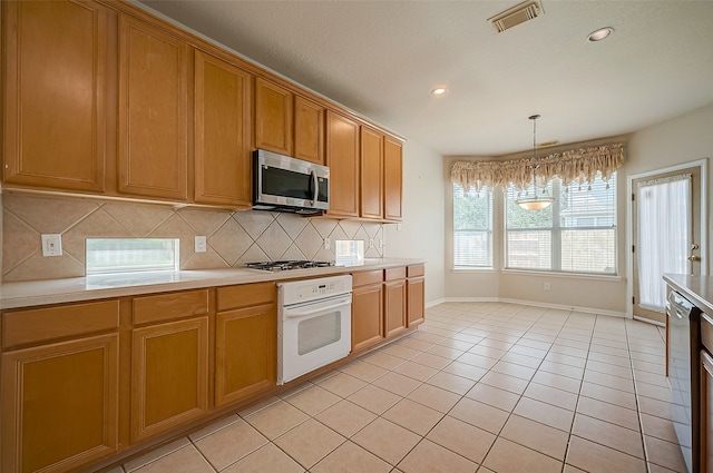 kitchen featuring light tile patterned floors, stainless steel appliances, decorative backsplash, and a chandelier