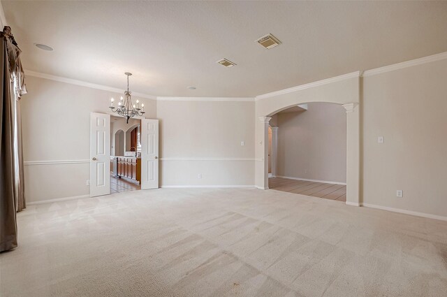 unfurnished room featuring ornate columns, ornamental molding, light carpet, and a chandelier