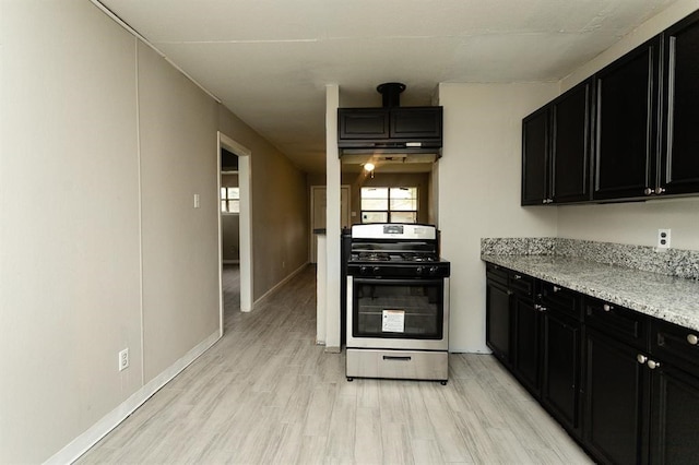 kitchen featuring light stone counters, stainless steel range, and light wood-type flooring