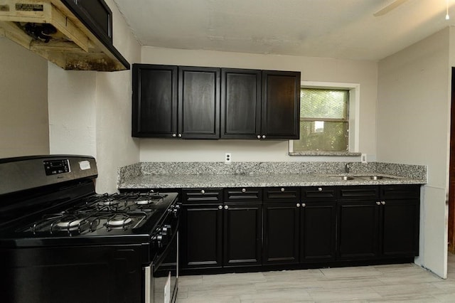 kitchen featuring sink, gas range, light stone counters, and custom range hood