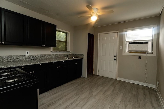 kitchen with ceiling fan, light hardwood / wood-style flooring, light stone counters, sink, and stove