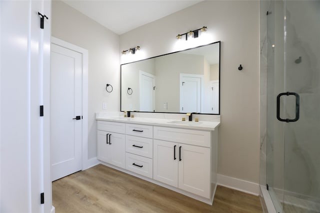 bathroom with hardwood / wood-style flooring, vanity, and a shower with shower door