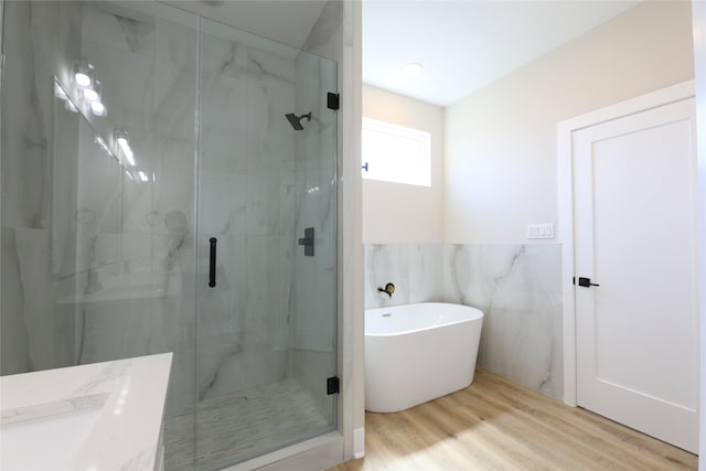 bathroom featuring tile walls, hardwood / wood-style floors, vanity, and separate shower and tub