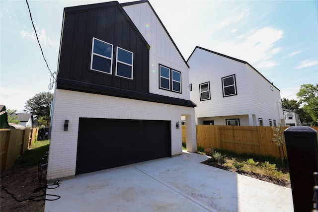 view of front of house featuring a garage, brick siding, board and batten siding, and fence