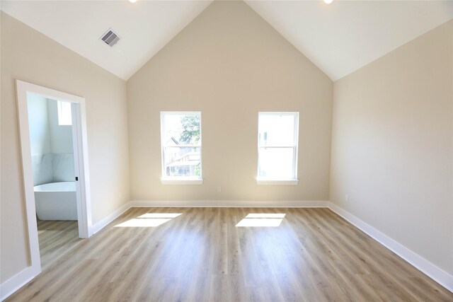 spare room with high vaulted ceiling and light wood-type flooring