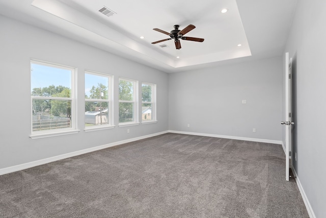 carpeted empty room with a tray ceiling and ceiling fan