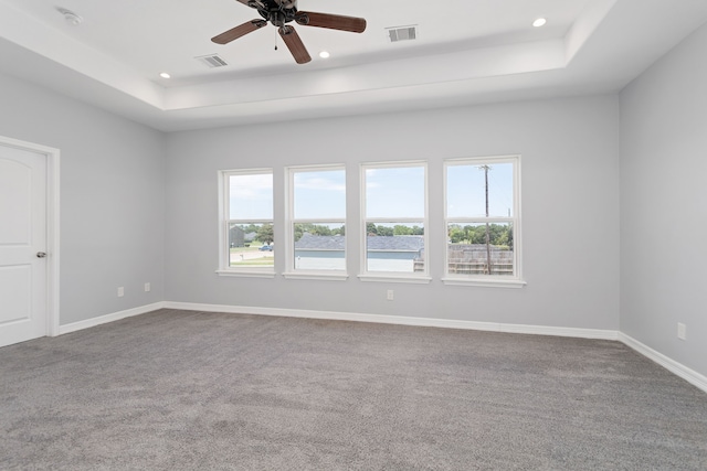 unfurnished room with ceiling fan, a raised ceiling, and carpet flooring