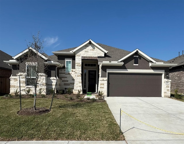 view of front facade with concrete driveway, stone siding, roof with shingles, an attached garage, and a front yard