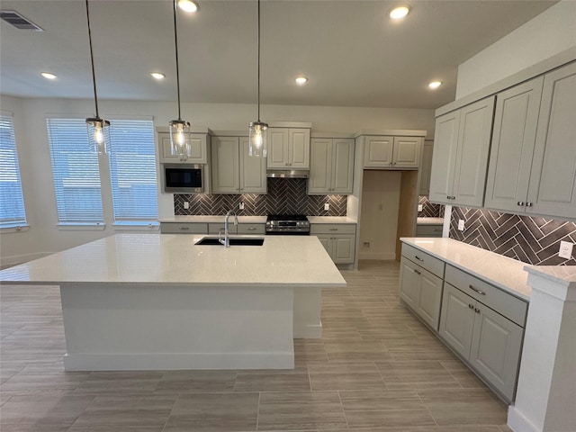 kitchen featuring light countertops, visible vents, appliances with stainless steel finishes, a sink, and an island with sink