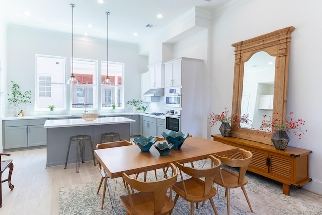 dining area with light wood-type flooring, sink, and ornamental molding