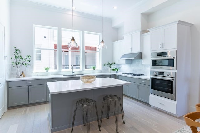 kitchen with a wealth of natural light, backsplash, double oven, and gray cabinets