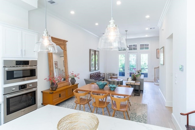 interior space featuring light hardwood / wood-style flooring, a towering ceiling, ornamental molding, and french doors