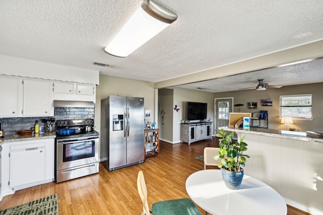 kitchen featuring light hardwood / wood-style floors, appliances with stainless steel finishes, tasteful backsplash, and white cabinets