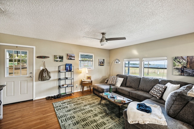 living room with a textured ceiling, ceiling fan, a healthy amount of sunlight, and wood-type flooring