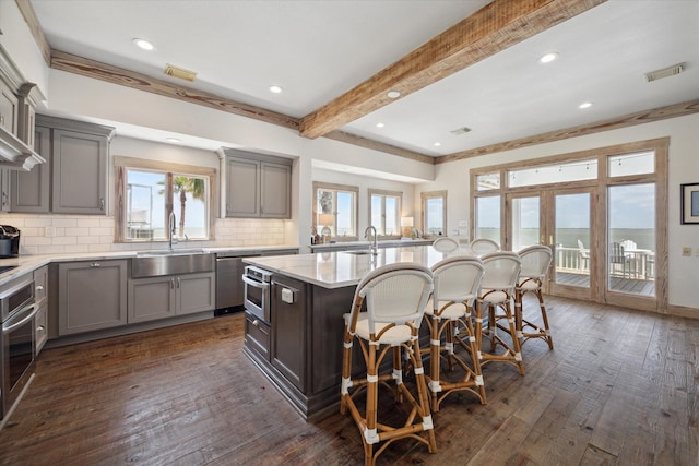 kitchen featuring decorative backsplash, dark hardwood / wood-style floors, sink, and an island with sink